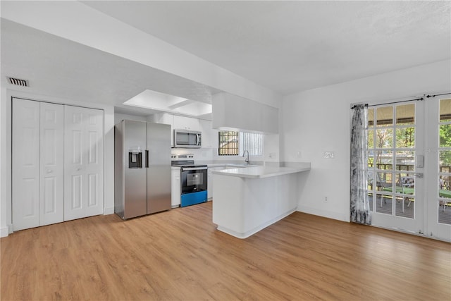 kitchen featuring light hardwood / wood-style floors, stainless steel appliances, a wealth of natural light, and kitchen peninsula