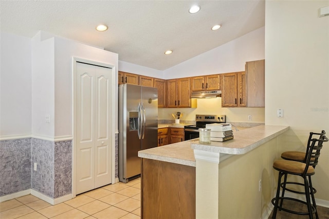 kitchen with kitchen peninsula, appliances with stainless steel finishes, a kitchen breakfast bar, vaulted ceiling, and light tile patterned flooring