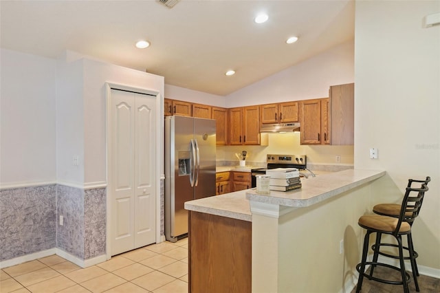 kitchen featuring kitchen peninsula, appliances with stainless steel finishes, a kitchen breakfast bar, and light tile patterned flooring