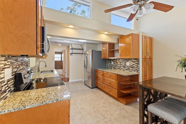 kitchen with light tile patterned floors, backsplash, stainless steel appliances, sink, and light stone counters