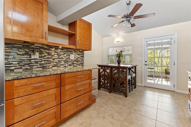 kitchen featuring light stone countertops, ceiling fan, light tile patterned floors, and tasteful backsplash