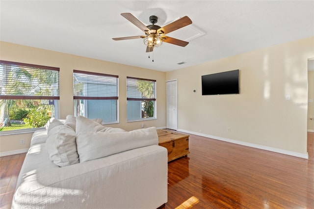 living room featuring dark wood-type flooring and ceiling fan