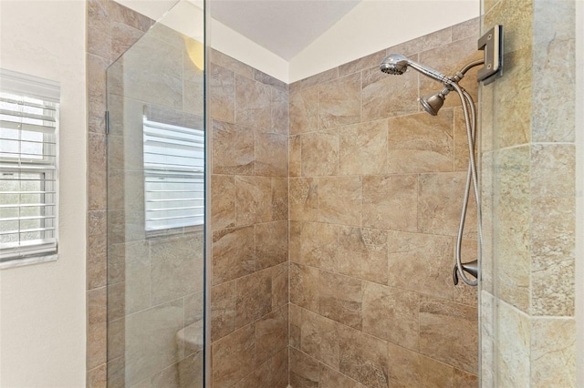 bathroom featuring lofted ceiling and tiled shower