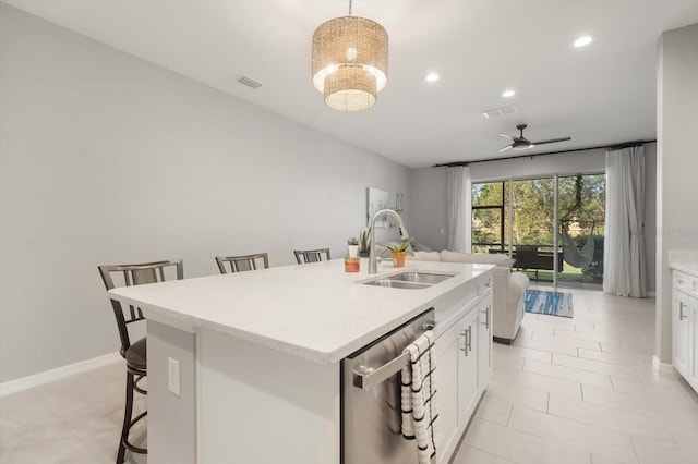 kitchen with a center island with sink, stainless steel dishwasher, a kitchen bar, decorative light fixtures, and sink