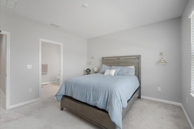 bedroom with connected bathroom and light carpet