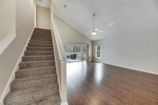 stairs featuring hardwood / wood-style floors, a textured ceiling, high vaulted ceiling, and ceiling fan