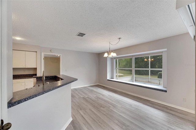 kitchen featuring light hardwood / wood-style floors, an inviting chandelier, a textured ceiling, and hanging light fixtures