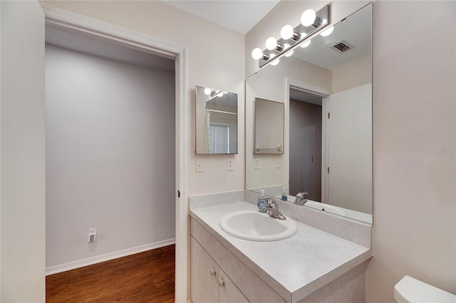 bathroom with vanity, toilet, and hardwood / wood-style floors