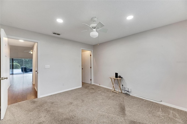 carpeted empty room featuring ceiling fan and a textured ceiling