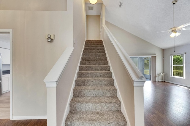 staircase featuring hardwood / wood-style floors, a textured ceiling, high vaulted ceiling, and ceiling fan