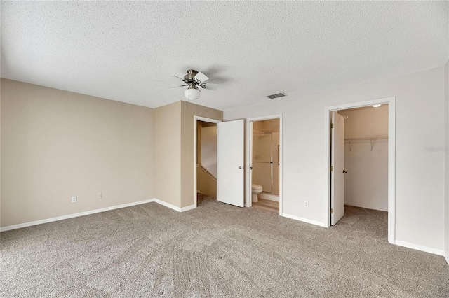 unfurnished bedroom with carpet flooring, a spacious closet, a closet, ceiling fan, and connected bathroom