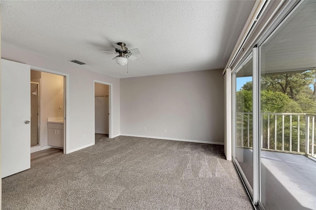 unfurnished bedroom with a closet, ceiling fan, carpet flooring, and a spacious closet