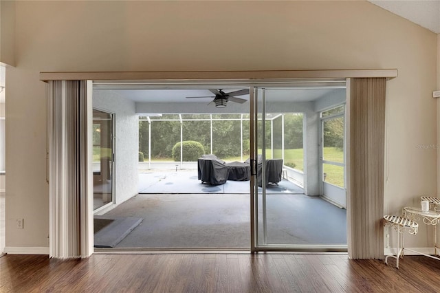 doorway to outside featuring dark wood-type flooring, vaulted ceiling, and ceiling fan