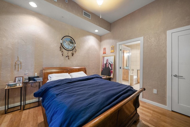 bedroom featuring hardwood / wood-style flooring and ensuite bathroom