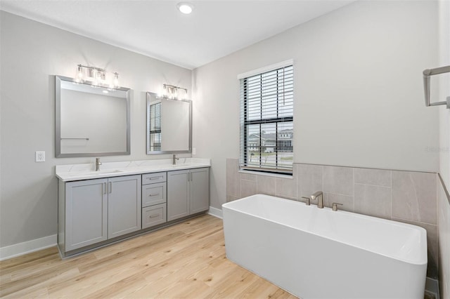 bathroom featuring vanity, hardwood / wood-style floors, and a bath