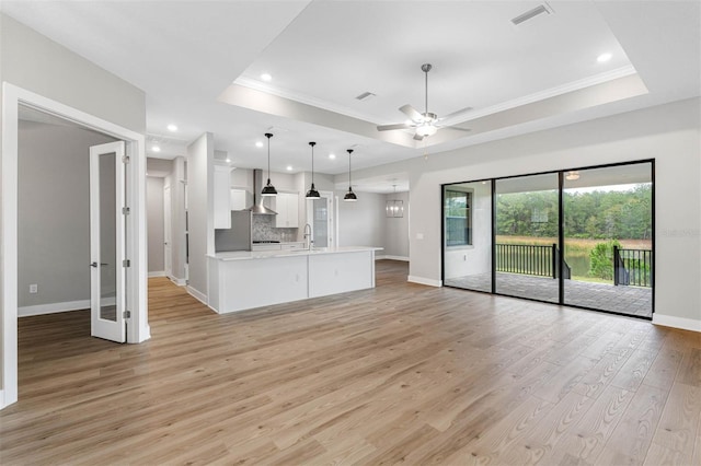 kitchen with light hardwood / wood-style flooring, white cabinetry, a raised ceiling, and pendant lighting