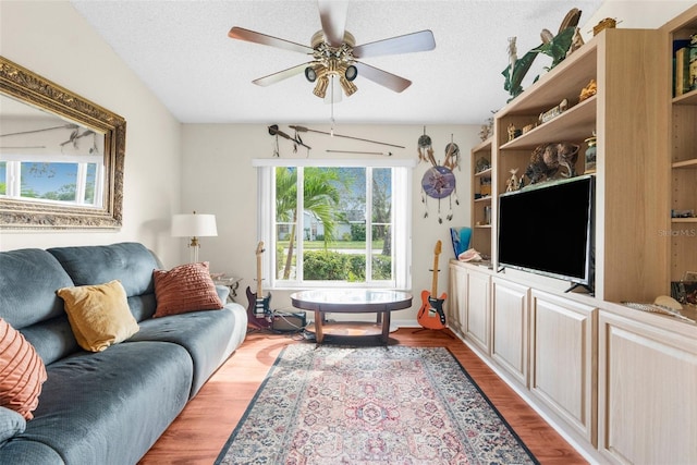 living room with ceiling fan, a textured ceiling, and light hardwood / wood-style floors