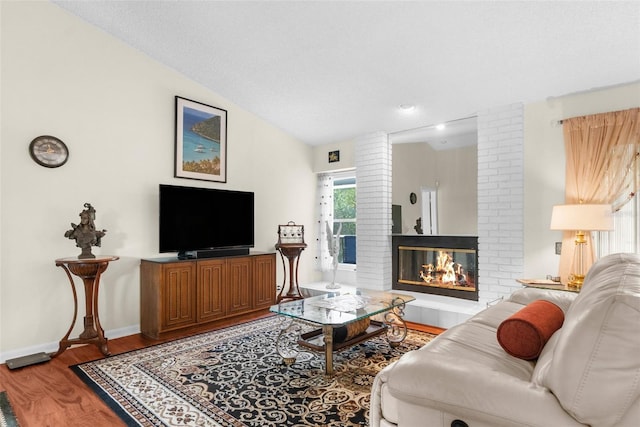 living room featuring vaulted ceiling, hardwood / wood-style floors, and a fireplace