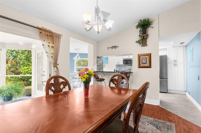 dining space with lofted ceiling, a notable chandelier, and light hardwood / wood-style floors