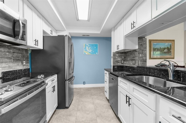 kitchen with dark stone countertops, appliances with stainless steel finishes, sink, and white cabinets