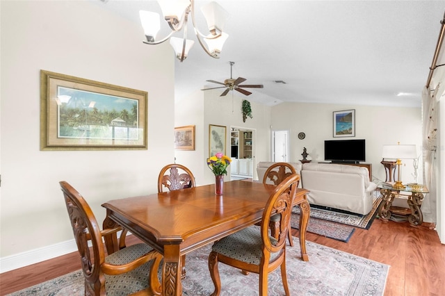 dining space featuring hardwood / wood-style flooring, lofted ceiling, and ceiling fan with notable chandelier