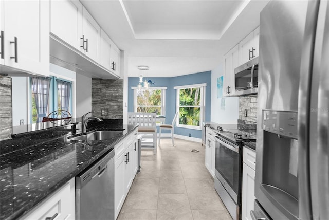 kitchen featuring appliances with stainless steel finishes, decorative light fixtures, sink, white cabinets, and a raised ceiling