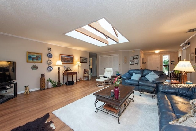 living room featuring crown molding, hardwood / wood-style flooring, and a skylight