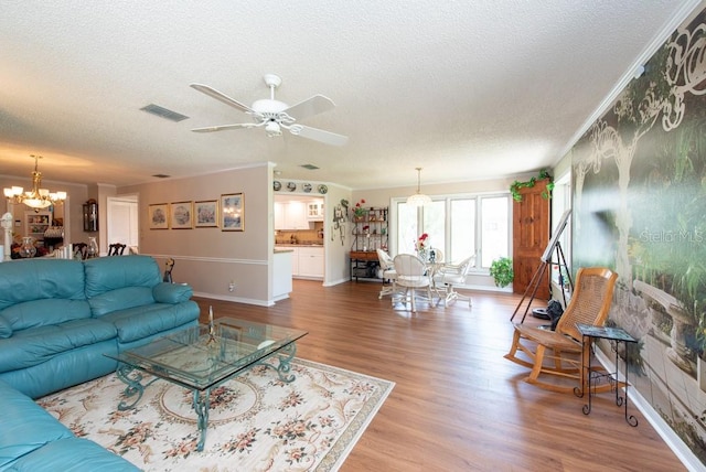 living room featuring crown molding, hardwood / wood-style floors, a textured ceiling, and ceiling fan with notable chandelier