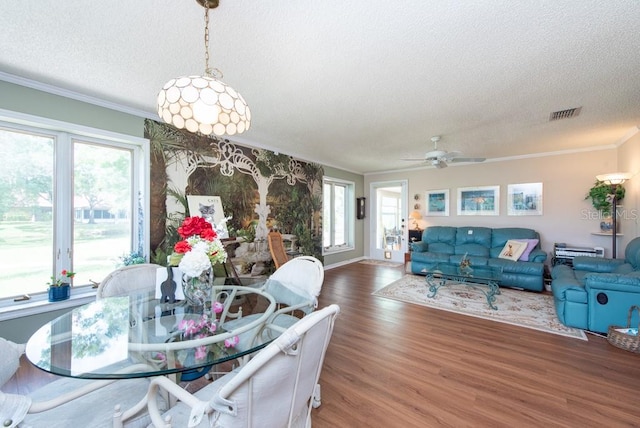 dining room with ceiling fan, hardwood / wood-style flooring, a textured ceiling, and crown molding