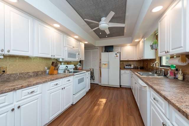 kitchen with tasteful backsplash, dark hardwood / wood-style flooring, white cabinetry, sink, and white appliances