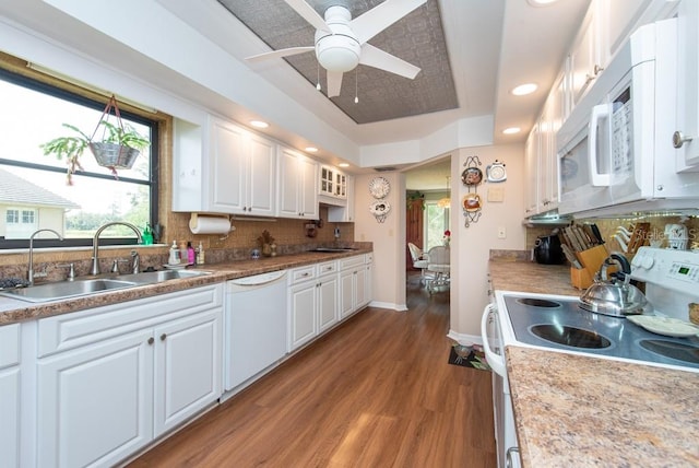 kitchen with decorative backsplash, hardwood / wood-style floors, white cabinetry, sink, and white appliances