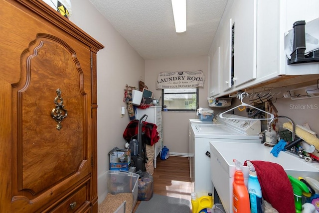 clothes washing area with cabinets, a textured ceiling, hardwood / wood-style flooring, washing machine and clothes dryer, and sink