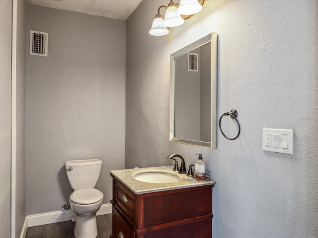 bathroom with hardwood / wood-style floors, vanity, a textured ceiling, and toilet