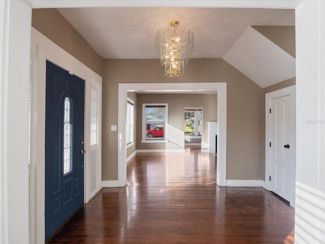 entryway with a chandelier, wood finished floors, lofted ceiling, and baseboards