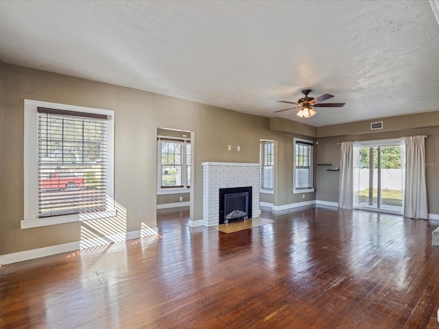 unfurnished living room with a fireplace, hardwood / wood-style floors, a textured ceiling, and a wealth of natural light