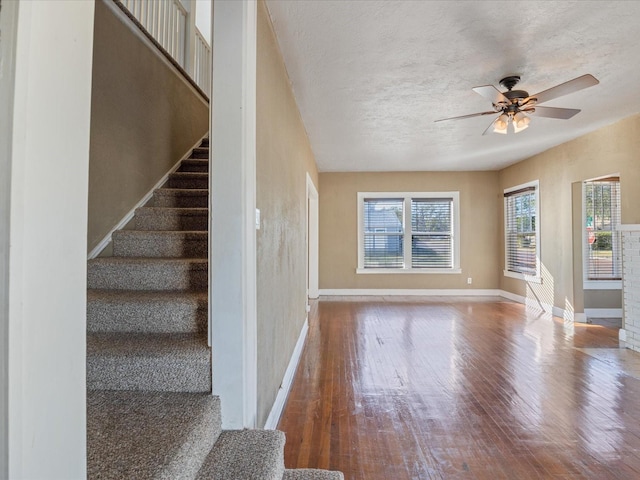 stairway with hardwood / wood-style floors, a textured ceiling, and ceiling fan