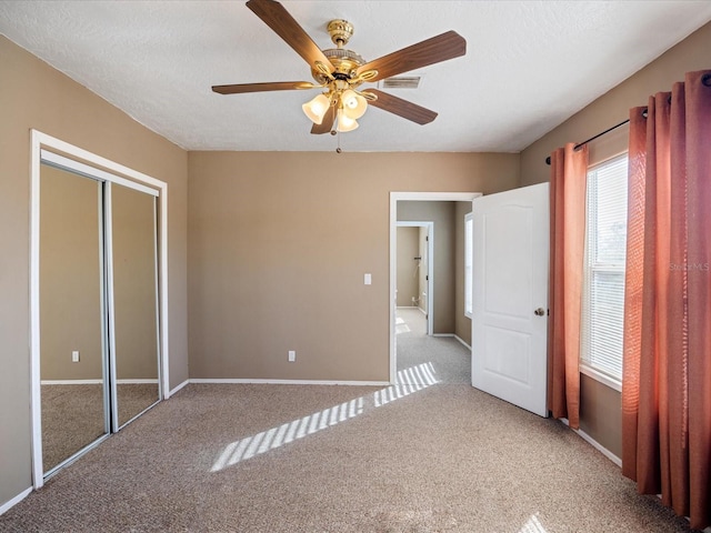 unfurnished bedroom with a textured ceiling, carpet flooring, visible vents, baseboards, and a closet