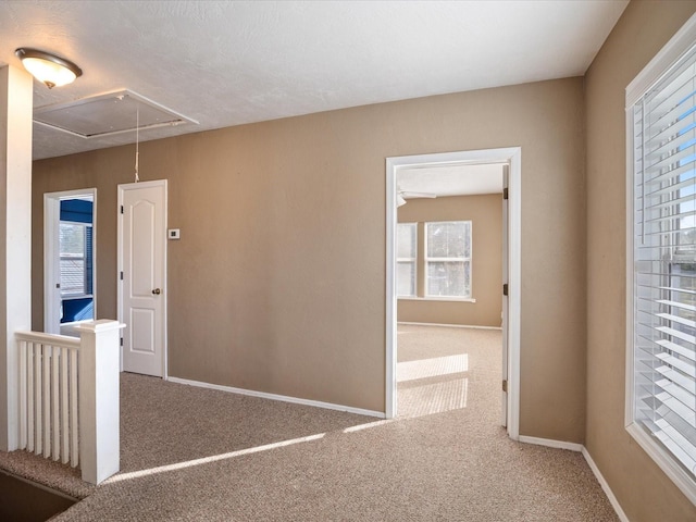 corridor with carpet floors, attic access, and baseboards