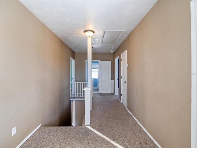 hall with carpet, attic access, and baseboards