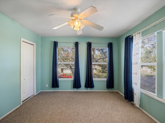 carpeted spare room with ceiling fan, a textured ceiling, and baseboards