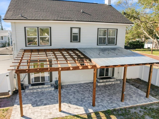 rear view of house featuring a patio area, a chimney, and fence