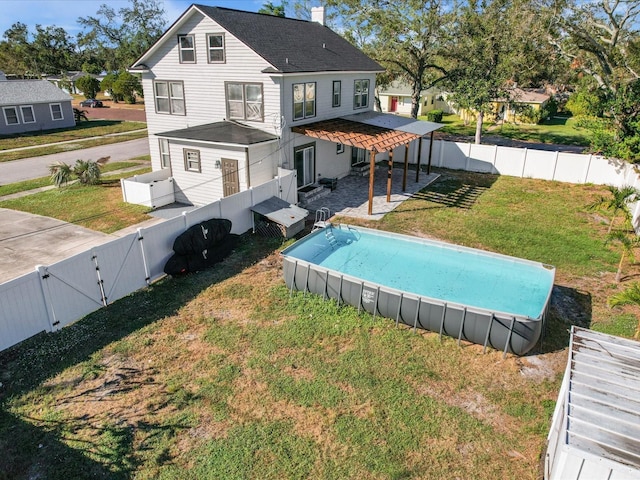 rear view of property featuring a yard, a chimney, a fenced backyard, and a gate