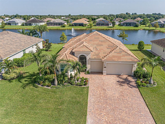 view of front facade featuring a front lawn, a garage, and a water view