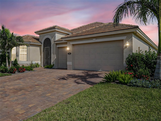 mediterranean / spanish-style home featuring a yard and a garage