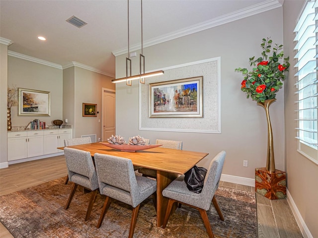 dining space with crown molding and light wood-type flooring