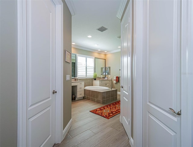 bathroom featuring a bath, crown molding, wood-type flooring, and vanity