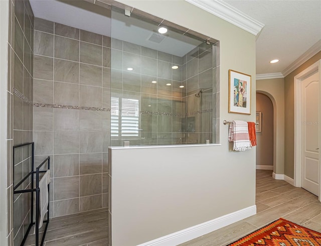 bathroom with a tile shower, ornamental molding, and hardwood / wood-style floors