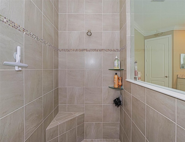 bathroom with ornamental molding and tiled shower