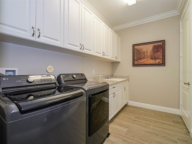 laundry room featuring sink, independent washer and dryer, light hardwood / wood-style floors, ornamental molding, and cabinets