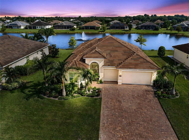 view of front of house with a yard, a garage, and a water view